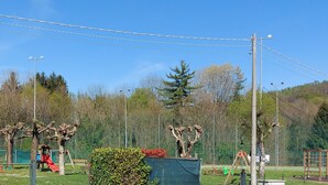 A playground with slides and swings, surrounded by trees and a fenced area. - The Umbrella Cat - Lake Maggiore (Carpugnino)