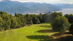 A golf course with a view of mountains and a lake. - The Umbrella Cat - Lake Maggiore (Carpugnino)