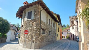 A narrow cobblestone street with stone buildings, a no entry sign, and a parked car. - The Umbrella Cat - Lake Maggiore (Carpugnino)
