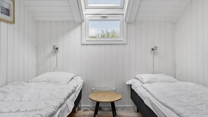 A room with two beds, a small round table, and a skylight.