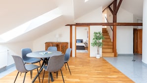 Un coin repas avec une table ronde et des chaises, un buffet en bois et un escalier menant à une autre pièce.
