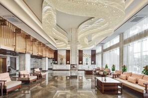 A spacious lobby with a polished marble floor, a reception desk, seating areas, and large windows allowing natural light. - Rose Garden International Hotel (Phnom Penh)