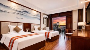 Une chambre d’hôtel avec deux lits, un bureau et un balcon offrant une vue sur la ville.