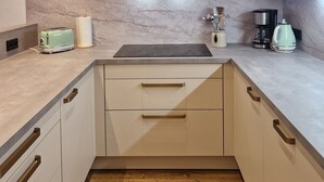 A modern kitchen with white cabinets, a stainless steel range hood, a toaster, a kettle, and a coffee maker on the countertop. - Modern, newly renovated Apartment in the heart of Ischgl (Ischgl)