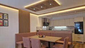 A modern kitchen with a wooden dining table and pink chairs, a built-in oven, and a refrigerator. - Modern, newly renovated Apartment in the heart of Ischgl (Ischgl)