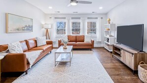 A spacious living room with two leather sofas, a coffee table, a flat-screen TV, and a ceiling fan. - Spacious unit near Downtown and Bourbon Trail! (Louisville)