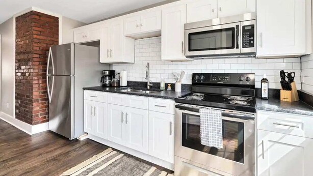 A modern kitchen with white cabinets, a stainless steel refrigerator, a microwave, and a stove. - Spacious unit near Downtown and Bourbon Trail! (Louisville)