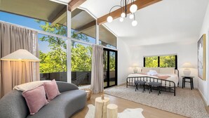 Une chambre moderne avec une grande fenêtre, un canapé, un lit et une petite table.
