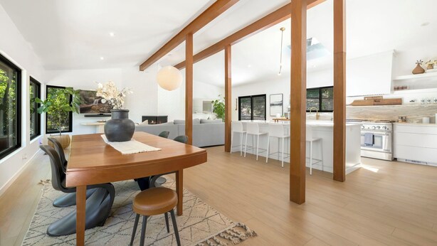 Un vaste espace de vie comprenant une table à manger en bois, des sièges confortables et une grande fenêtre donnant sur l’extérieur.