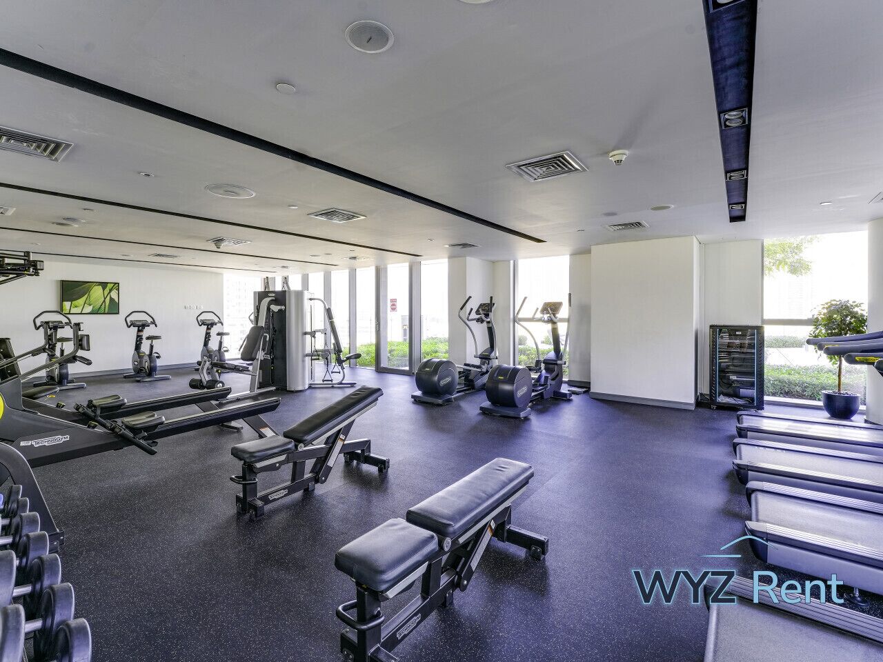 Un gimnasio con diverso equipo de ejercicio, ventanas amplias y un diseño moderno y limpio.