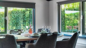 A dining area with a table set for four, surrounded by large windows offering a view of greenery. - 3 bedroom amazing home in Heinkenszand (Heinkenszand)