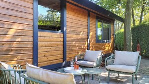 A wooden exterior wall with large windows and a patio area with outdoor furniture. - 3 bedroom amazing home in Heinkenszand (Heinkenszand)