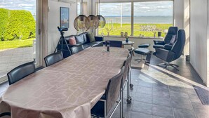 A modern dining area with a large table, black chairs, and a view of the sea. - Lovely home in Fur with sauna (Fur)