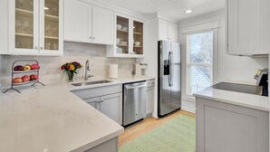 A modern kitchen with white cabinetry, stainless steel appliances, and a marble countertop. - Award-Winning Resort Amenities | Racquet Club Villa 35 (Isle of Palms)