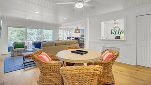 A spacious living room with a round table, wicker chairs, a ceiling fan, and large windows. - Award-Winning Resort Amenities | Racquet Club Villa 35 (Isle of Palms)