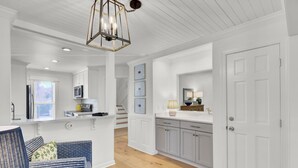 A modern kitchen with white cabinetry, a central island, and a hanging light fixture. - Award-Winning Resort Amenities | Racquet Club Villa 35 (Isle of Palms)