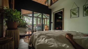 Un dormitorio con una cama grande, una planta en maceta y vistas al exterior.