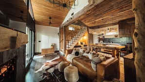 Ein rustikales Interieur mit Ledersofa, Holzbalken, Kamin und Küchenzeile.