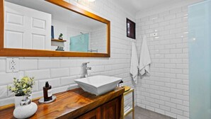 A bathroom with a white sink, wooden vanity, and a large mirror. - Classy Condo in the heart of town (Tamarindo)