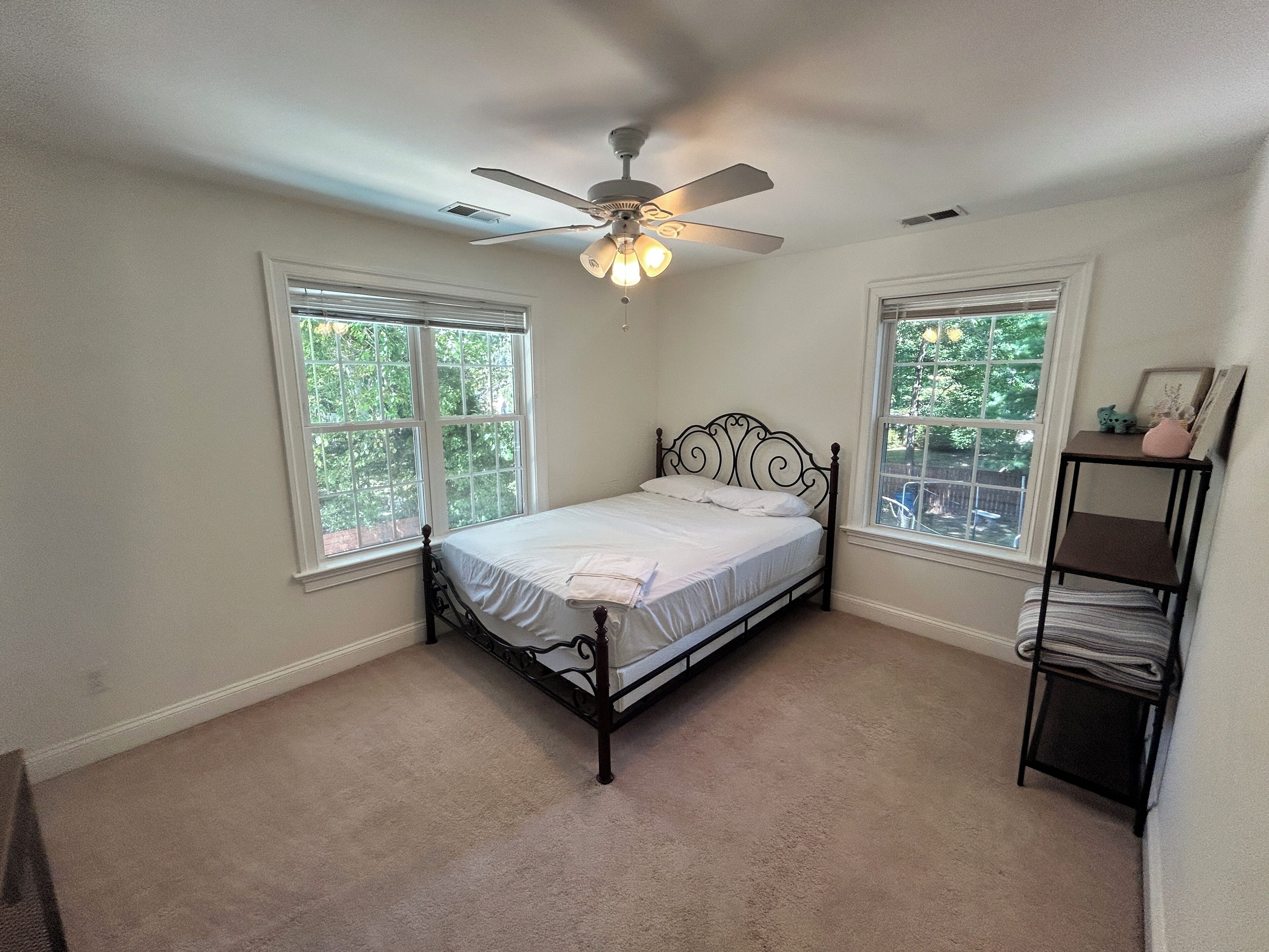 A bedroom with a bed, a ceiling fan, and two windows.