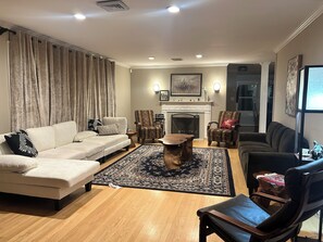 Una sala de estar con un sofá color beige, sillones estampados, una mesa de centro y una chimenea.