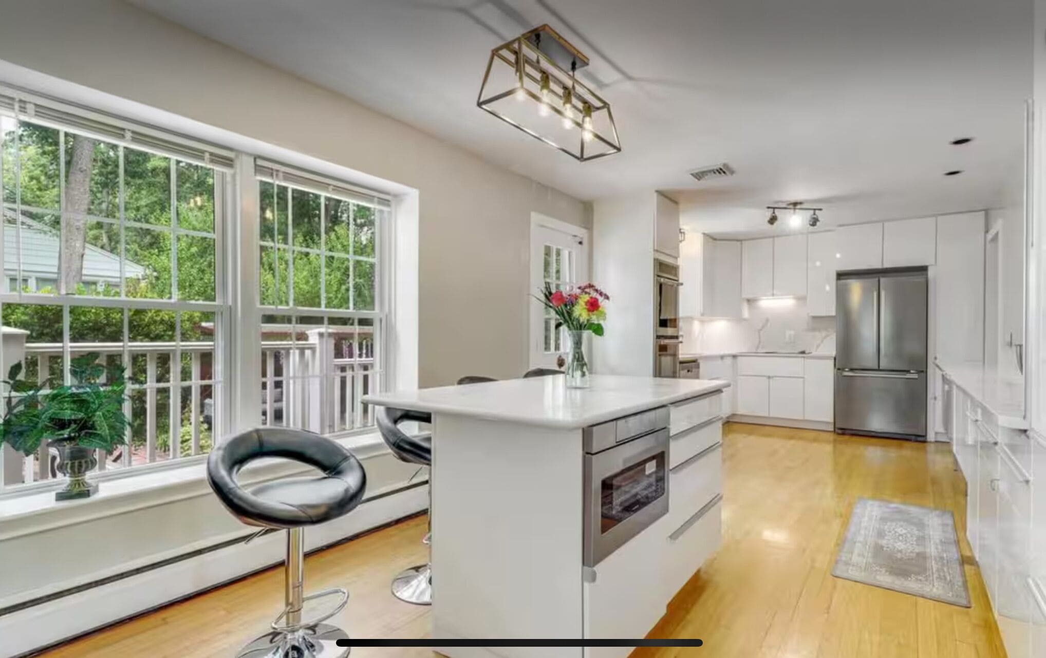 A modern kitchen with white cabinetry, a central island, and a large window.