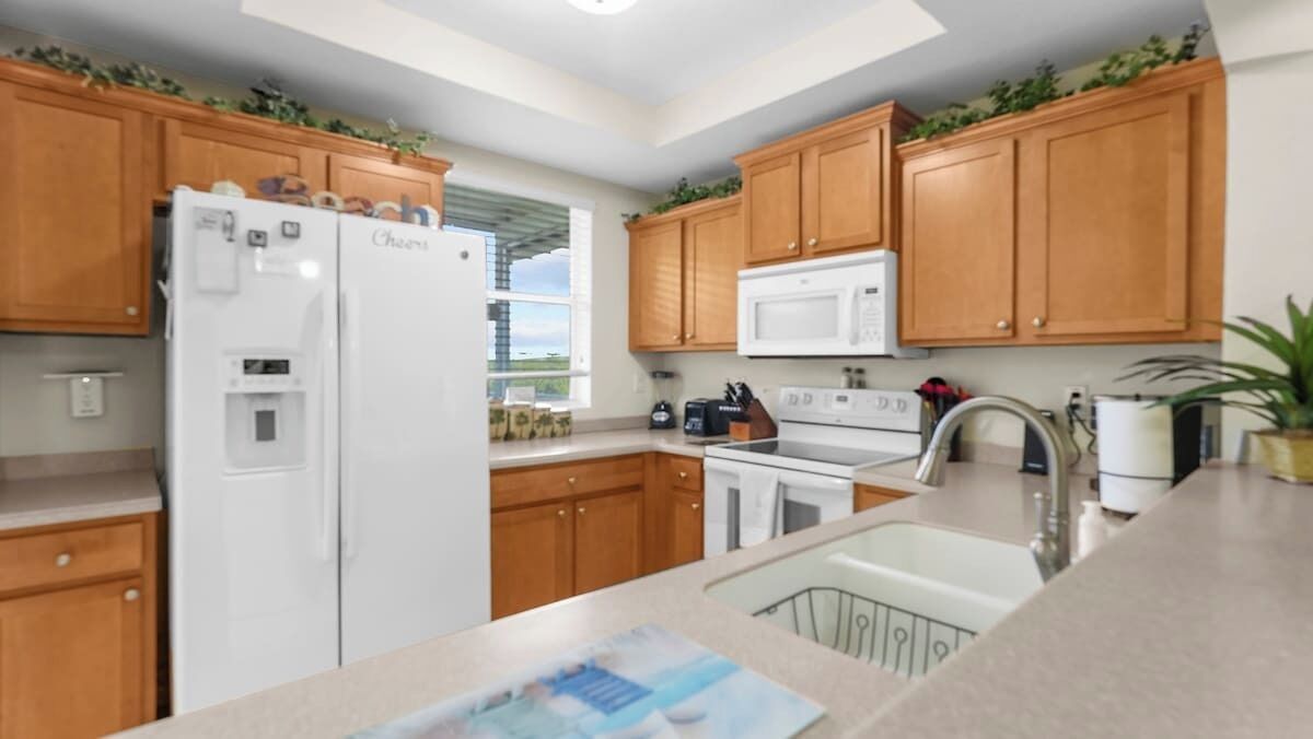 A modern kitchen with wooden cabinets, a white refrigerator, a microwave, and a sink.