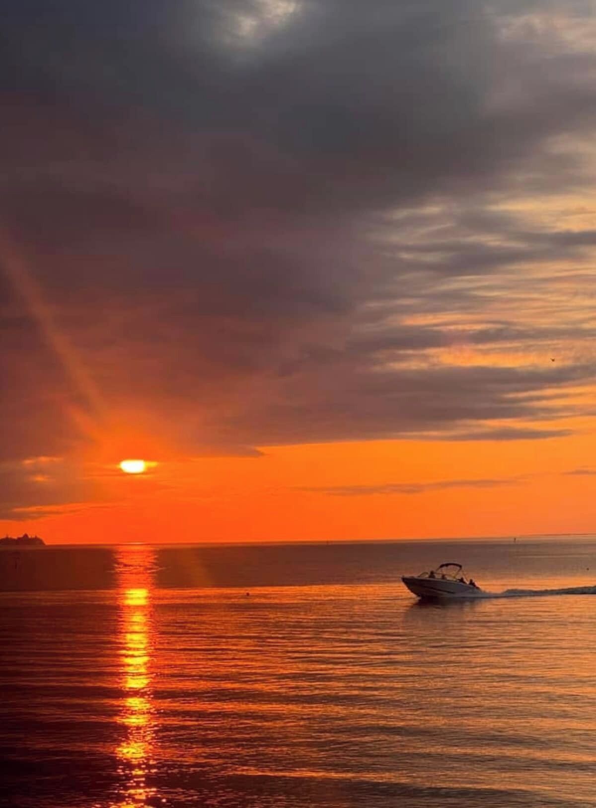 A sunset over a calm body of water with a boat.