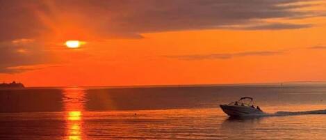 A sunset over a calm body of water with a boat.