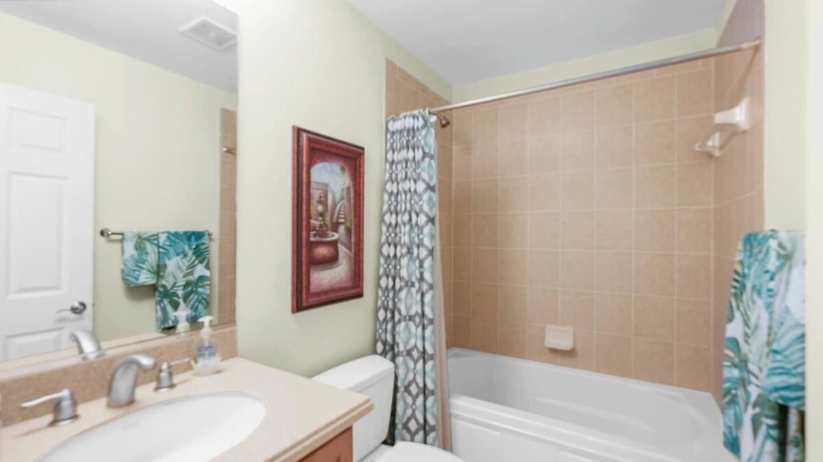A bathroom with a sink, mirror, toilet, and bathtub.