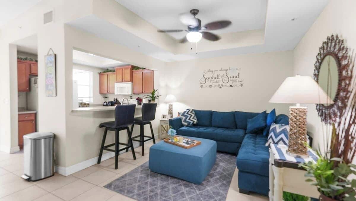 Una sala de estar con un sofá azul, una mesita de centro y una zona de comedor con dos sillas.