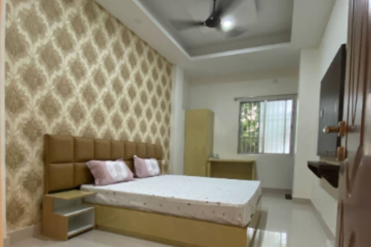 Une chambre avec un grand lit, une armoire, un ventilateur de plafond et une fenêtre avec des stores.