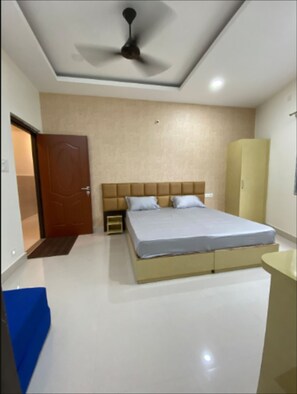 Ein Schlafzimmer mit Bett, Kleiderschrank, Deckenventilator und Tür.