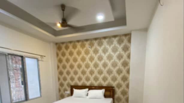 A bedroom with a bed, a desk, a chair, and a ceiling fan. - Matree Grand Lodge By GRB (Guwahati)