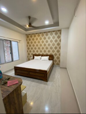 A bedroom with a bed, a desk, a chair, and a ceiling fan.