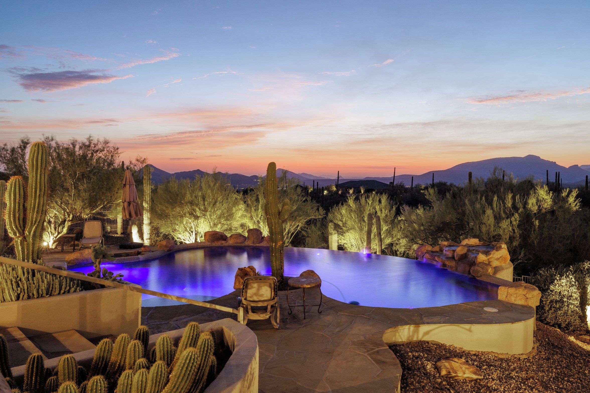 A nighttime outdoor pool area with a view of mountains in the background.