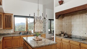 Una cucina moderna con mobili in legno, piani in granito, un'isola centrale e vista sul paesaggio desertico.