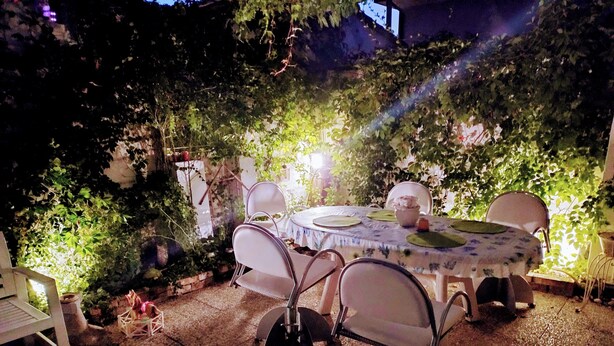 Eine einladende Terrassengruppe mit rundem Tisch und Stühlen, umgeben von viel Grün und sanfter Beleuchtung.