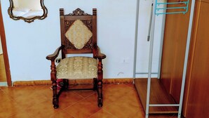 Ein Zimmer mit einem Holzhocker, einem Metallkleiderständer, einer Dekotasse und einem Spiegel an der Wand.