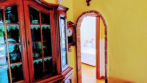 Ein Zimmer mit einem Holzschrank, einer Uhr und einem zur nächsten Kammer führenden Durchgang.