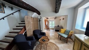 A spacious living area with a staircase, a sofa, a coffee table, and a television. - Charming provençal farmhouse with swimming pool, in the countryside by the river (Le Thoronet)