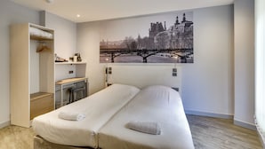 Une chambre d’hôtel moderne, dotée d’un grand lit, d’un bureau et d’une armoire.