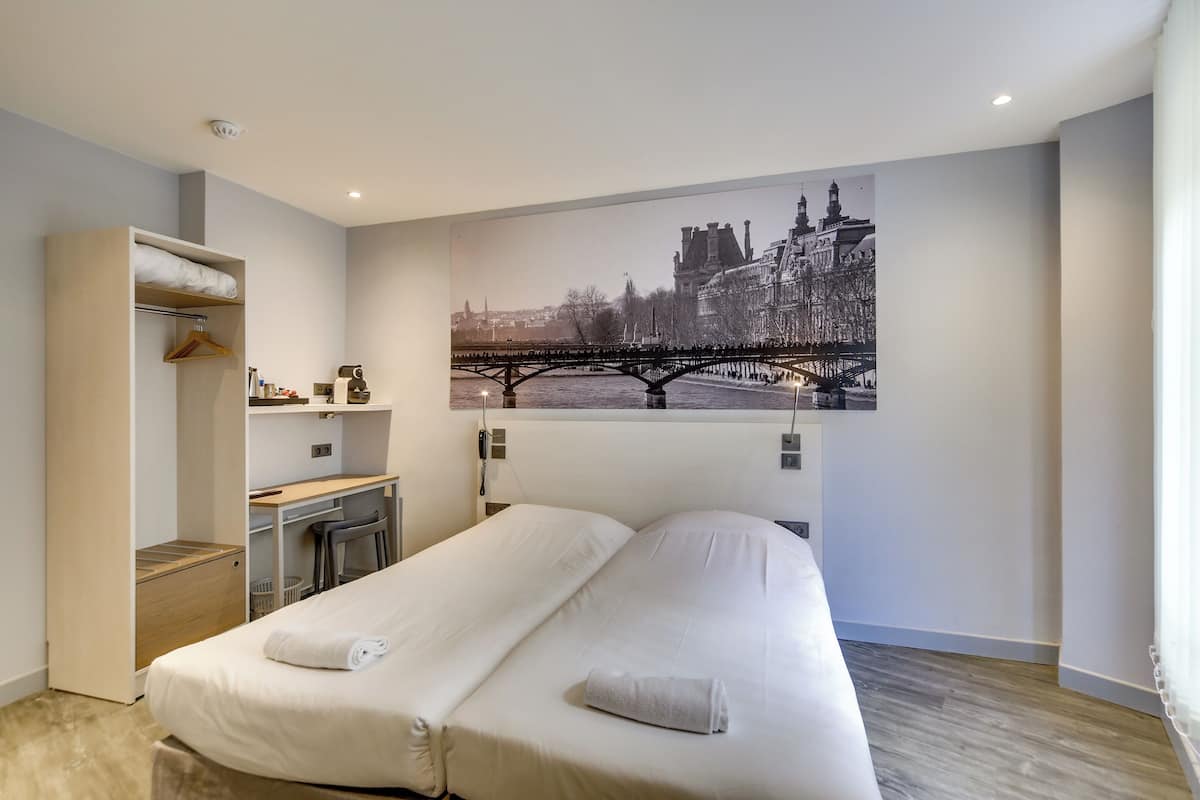 Una moderna camera d'albergo con un ampio letto, una scrivania e un armadio.