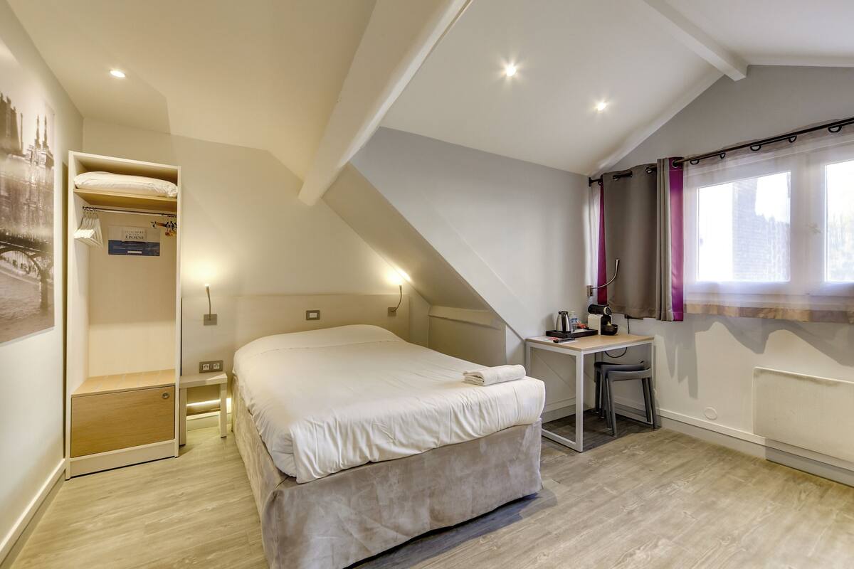 Una camera da letto con un letto, una scrivania, una sedia e una finestra con tende.