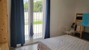 A bedroom with a bed, a chair, a small table, and a window with curtains. - Apulia Sea Punta Prosciutto (Punta Prosciutto)