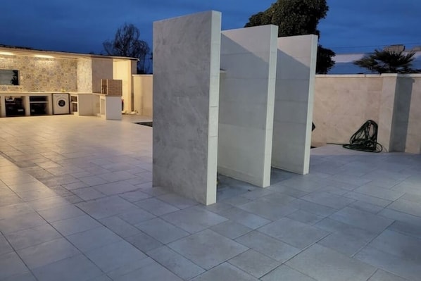 An outdoor area with a tiled floor, a washing machine, and a hose reel.
