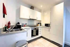 A modern kitchen with white cabinets, a stainless steel sink, a microwave, and a toaster.