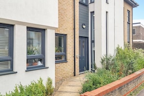 A modern townhouse with a brick facade, large windows, and a small front garden.
