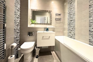 A modern bathroom with a toilet, sink, and shower.