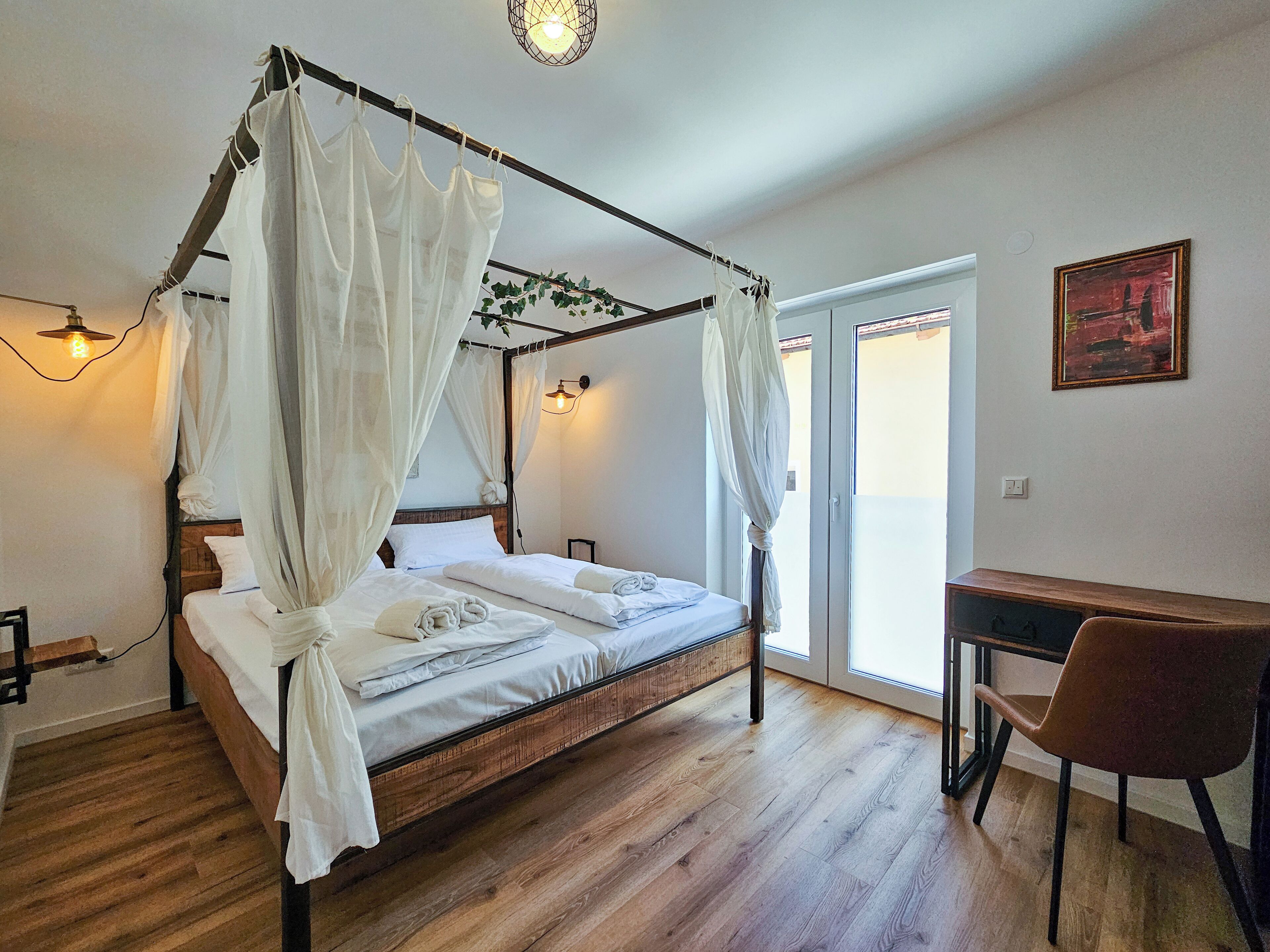 A bedroom with a four-poster bed, a desk, and a chair.